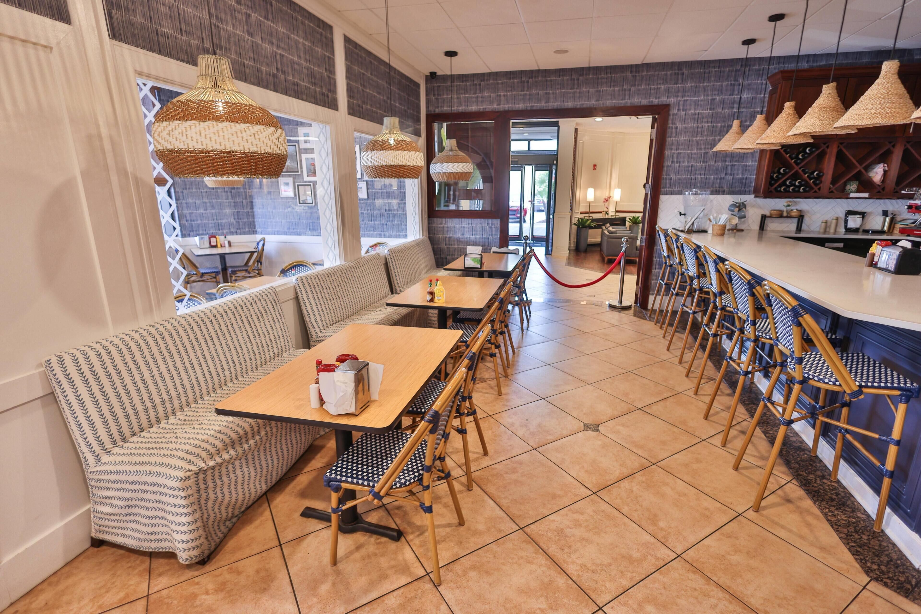 A restaurant with a bar area, seating arrangements, and a view through the door.