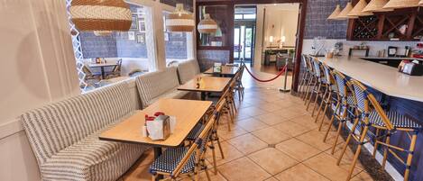 A restaurant with a bar area, seating arrangements, and a view through the door.