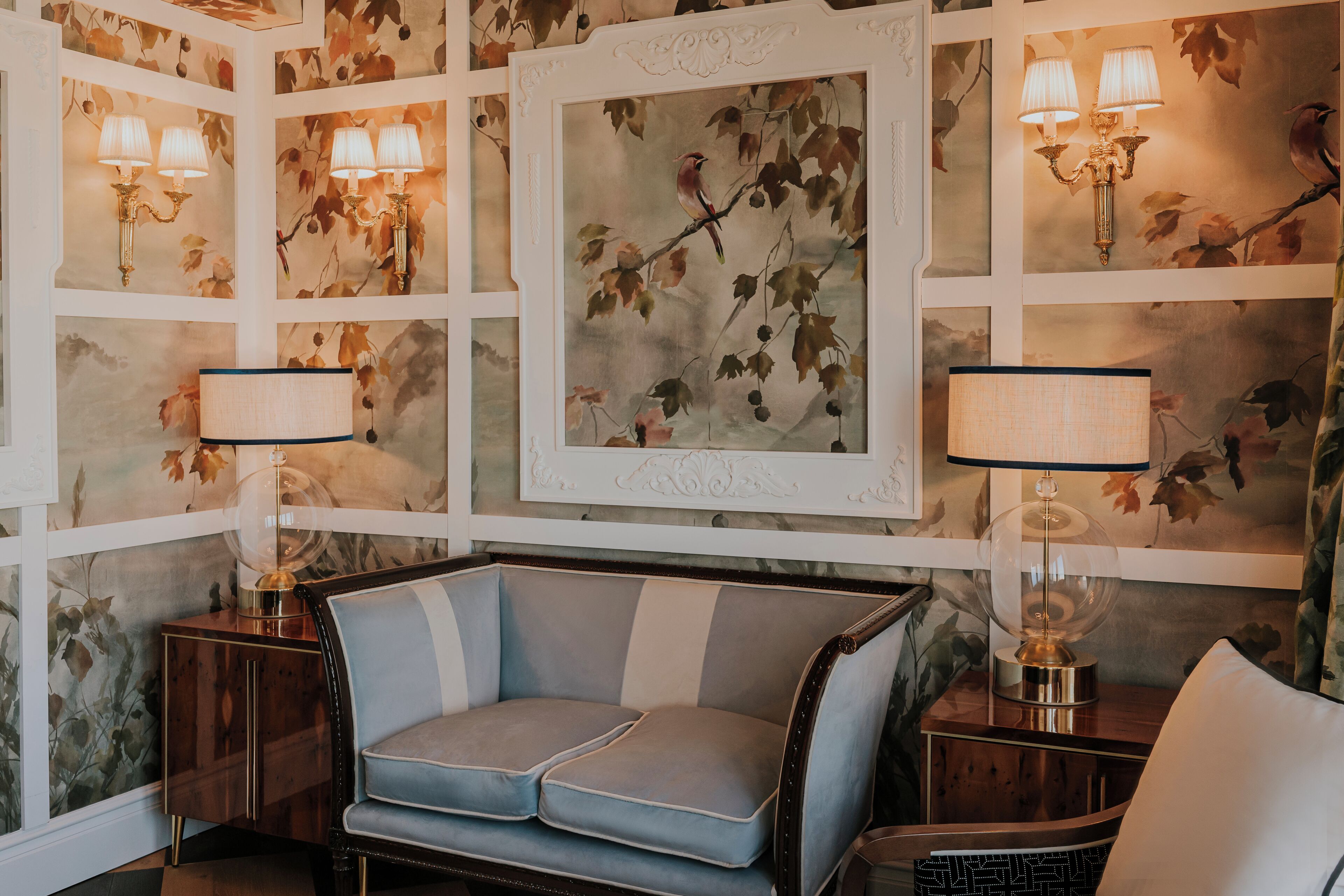 A room with a sofa, two lamps, and a framed picture on the wall.