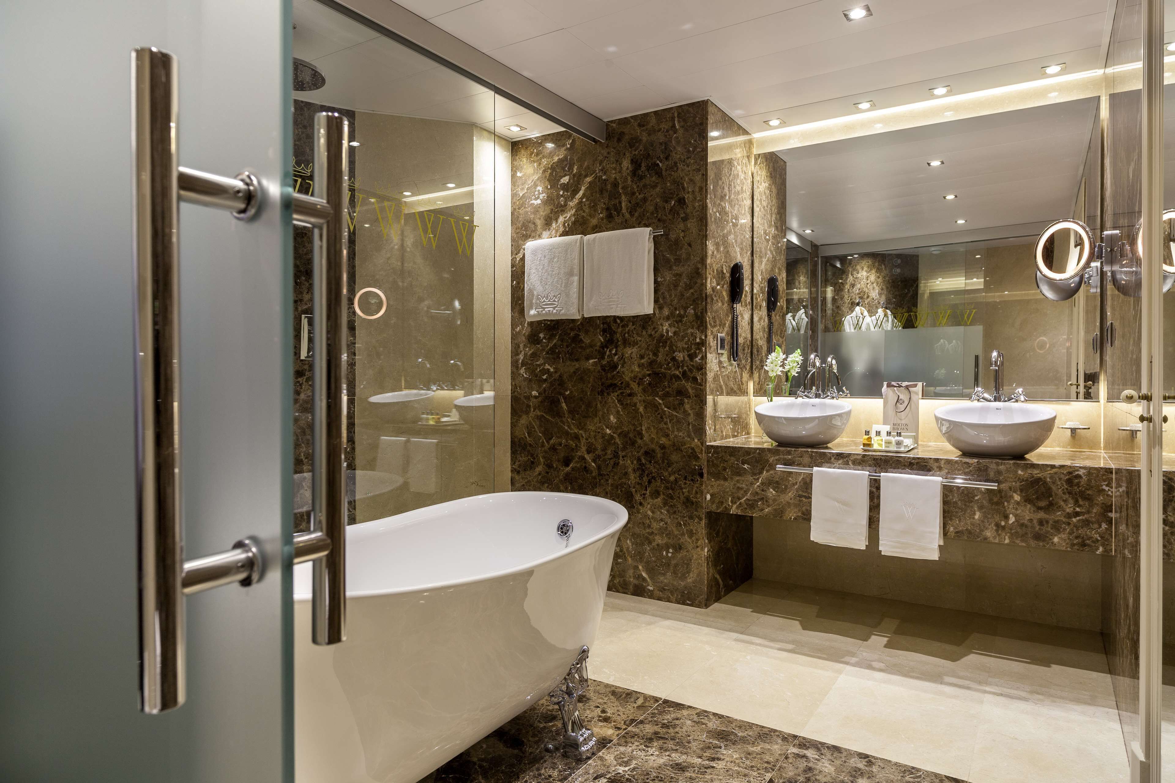 Een moderne badkamer met een vrijstaand bad, twee wasbakken en een douchecabine van glas.