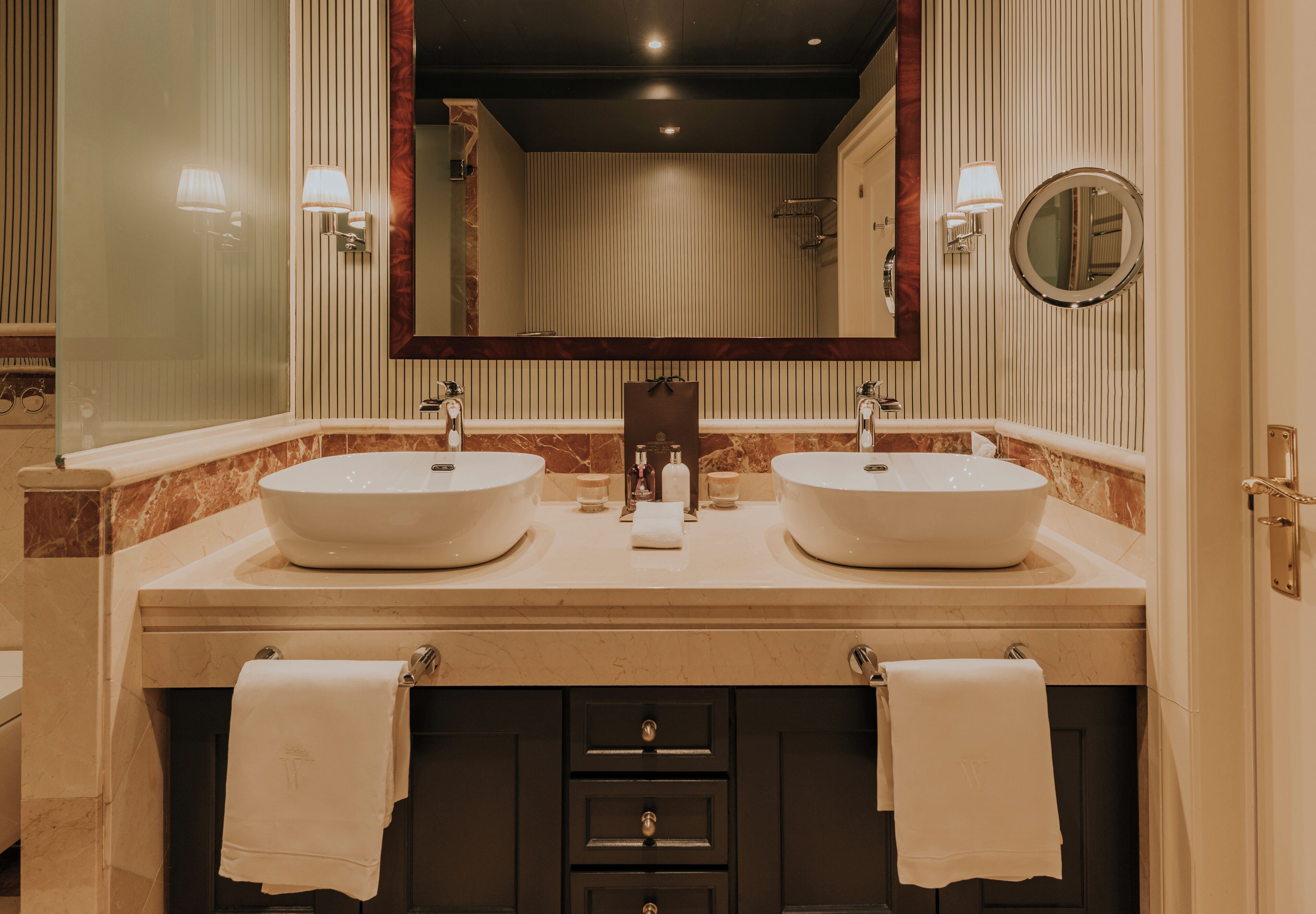 A bathroom with two sinks, a large mirror, and a towel rack.