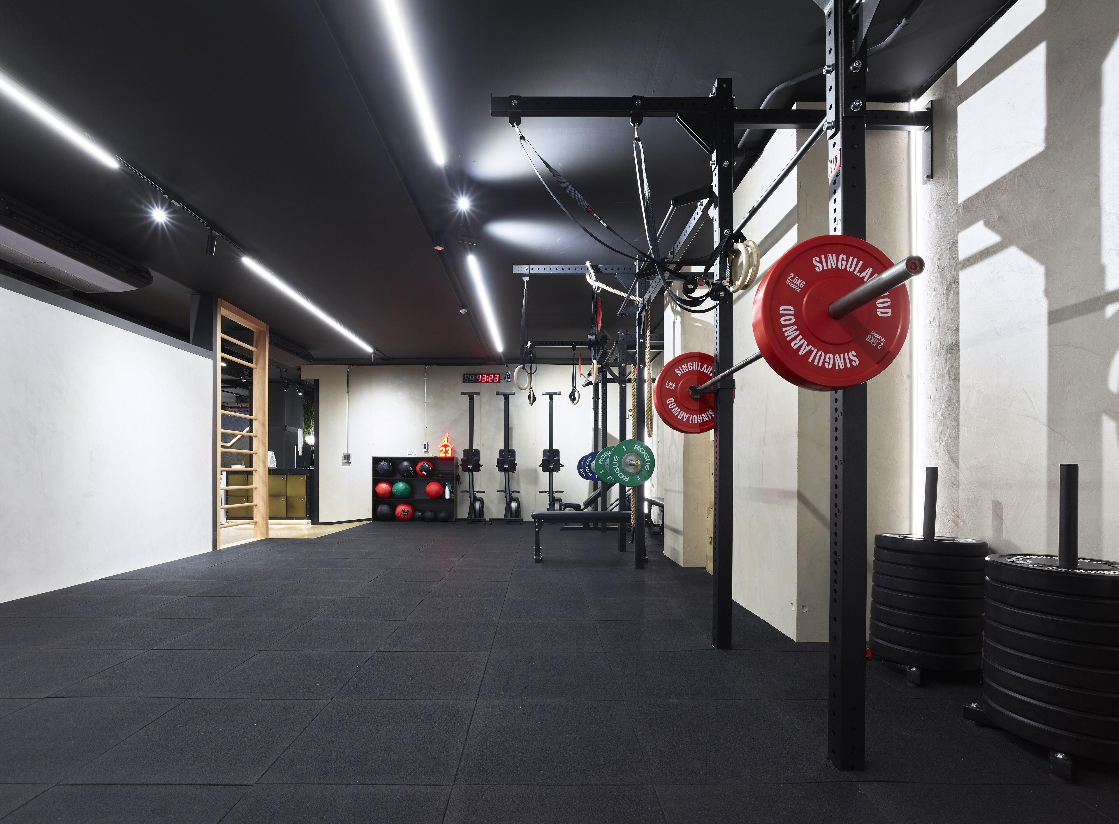 Een sportschool met gewichthefapparatuur, een digitale klok en een opbergrek.