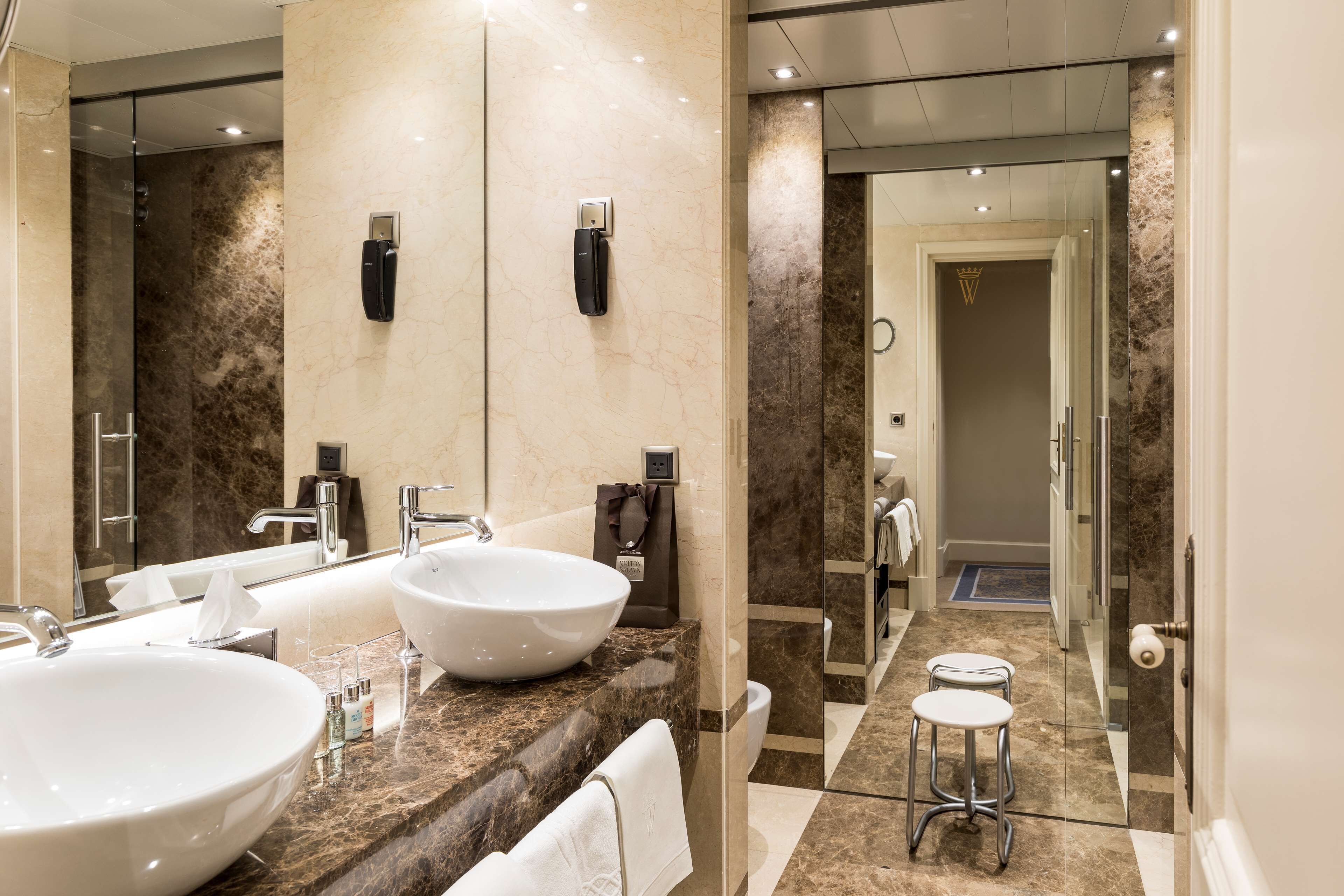 Une salle de bain moderne avec deux grands lavabos, une douche en verre et un miroir agrémenté d’un éclairage décoratif.