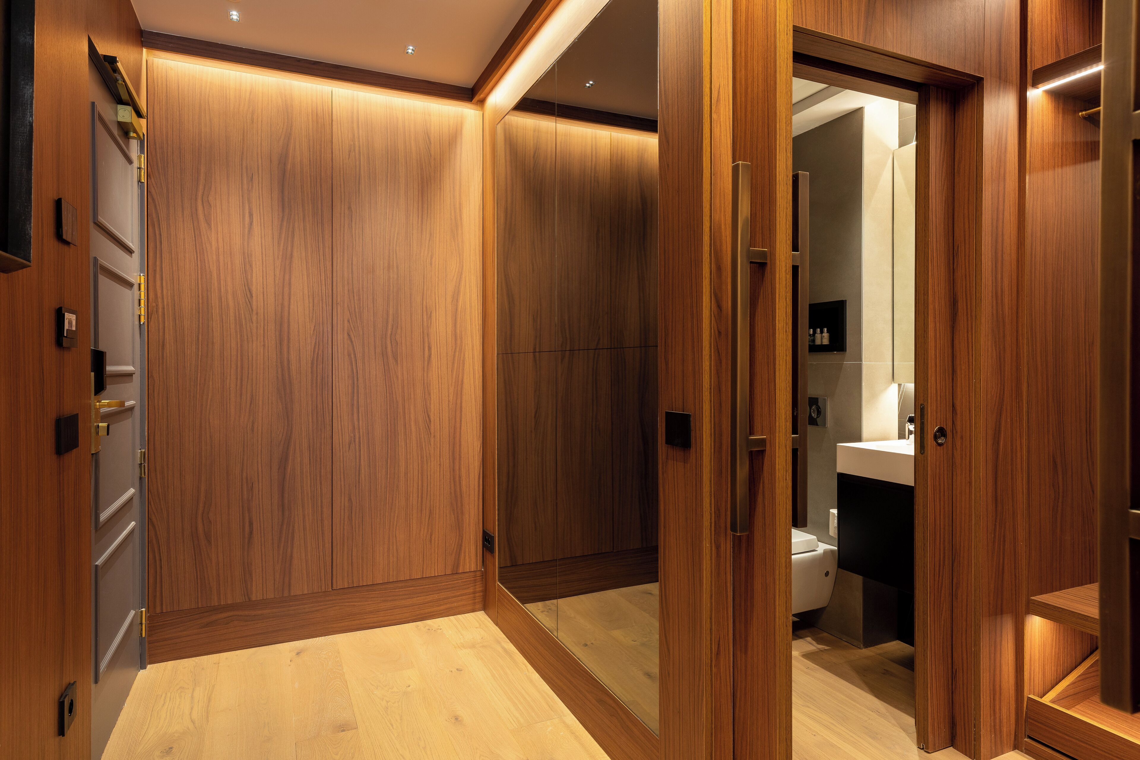 Una habitación moderna y bien iluminada con paneles de madera y un baño visible con lavamanos e inodoro.