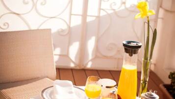 Ein Frühstückstisch auf einem Balkon für zwei Personen, mit Croissants, Orangensaft und einer Kaffeekanne.
