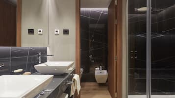 A modern bathroom with a large mirror, two sinks, and a shower area.