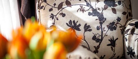 A sofa with a floral pattern and a vase of orange flowers in the foreground.