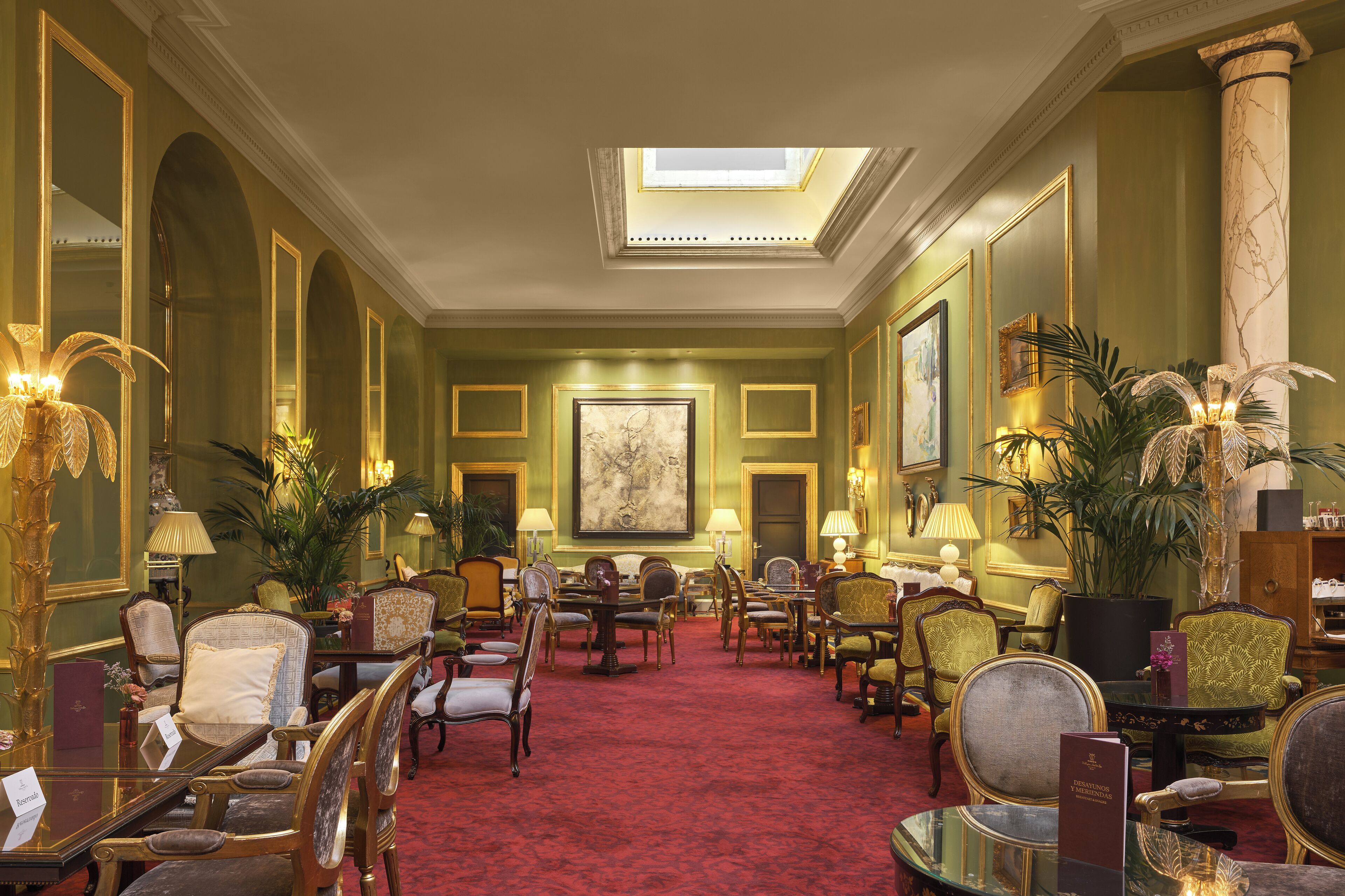 A spacious hotel lobby with a red carpet, multiple seating areas, and a skylight.