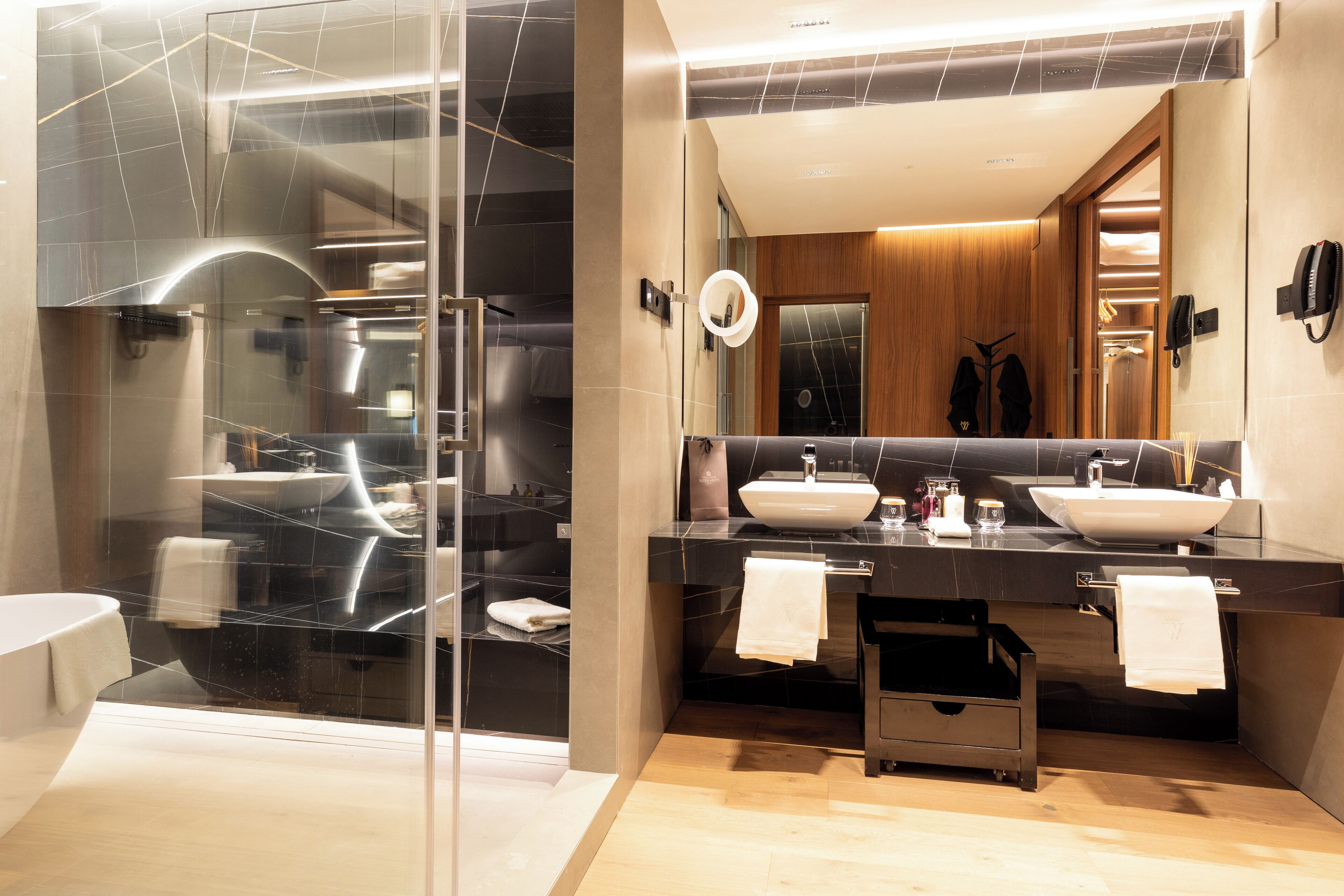 A modern bathroom with two sinks, a glass shower enclosure, and a wooden vanity.