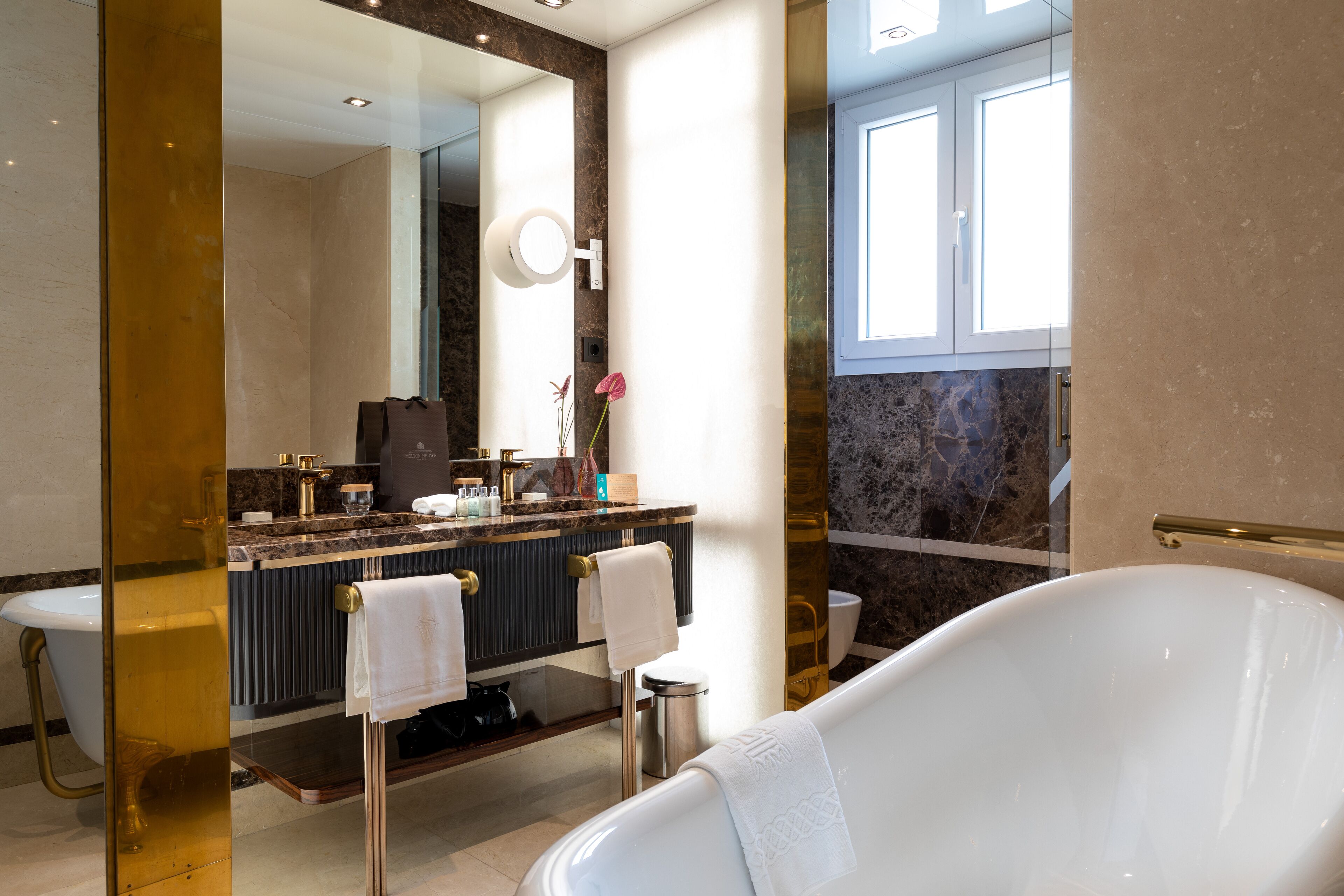 Un bagno moderno con una vasca freestanding, un mobile lavabo con piano in marmo e un grande specchio.