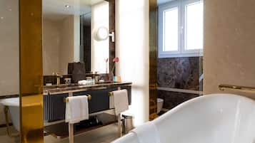 Un bagno moderno con una vasca freestanding, un mobile lavabo con piano in marmo e un grande specchio.