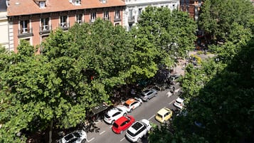 A street view with parked cars and trees lining the road.