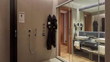 Un baño moderno con cabina de ducha de vidrio, un espejo grande y un tocador con lavabo y toallero.