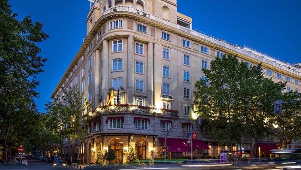 Un hotel histórico con un estilo arquitectónico clásico, que destaca por su entrada en esquina, varios balcones y una fachada bien iluminada.