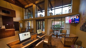 A spacious lobby with a reception desk, multiple seating areas, and a television displaying a news program. - DoubleTree Suites by Hilton Tucson - Williams Center (Tucson)