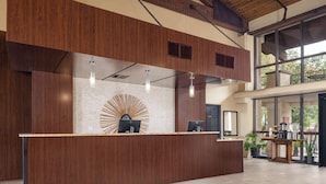 A reception desk with a modern design, featuring a wooden finish and a central decorative element. - DoubleTree Suites by Hilton Tucson - Williams Center (Tucson)
