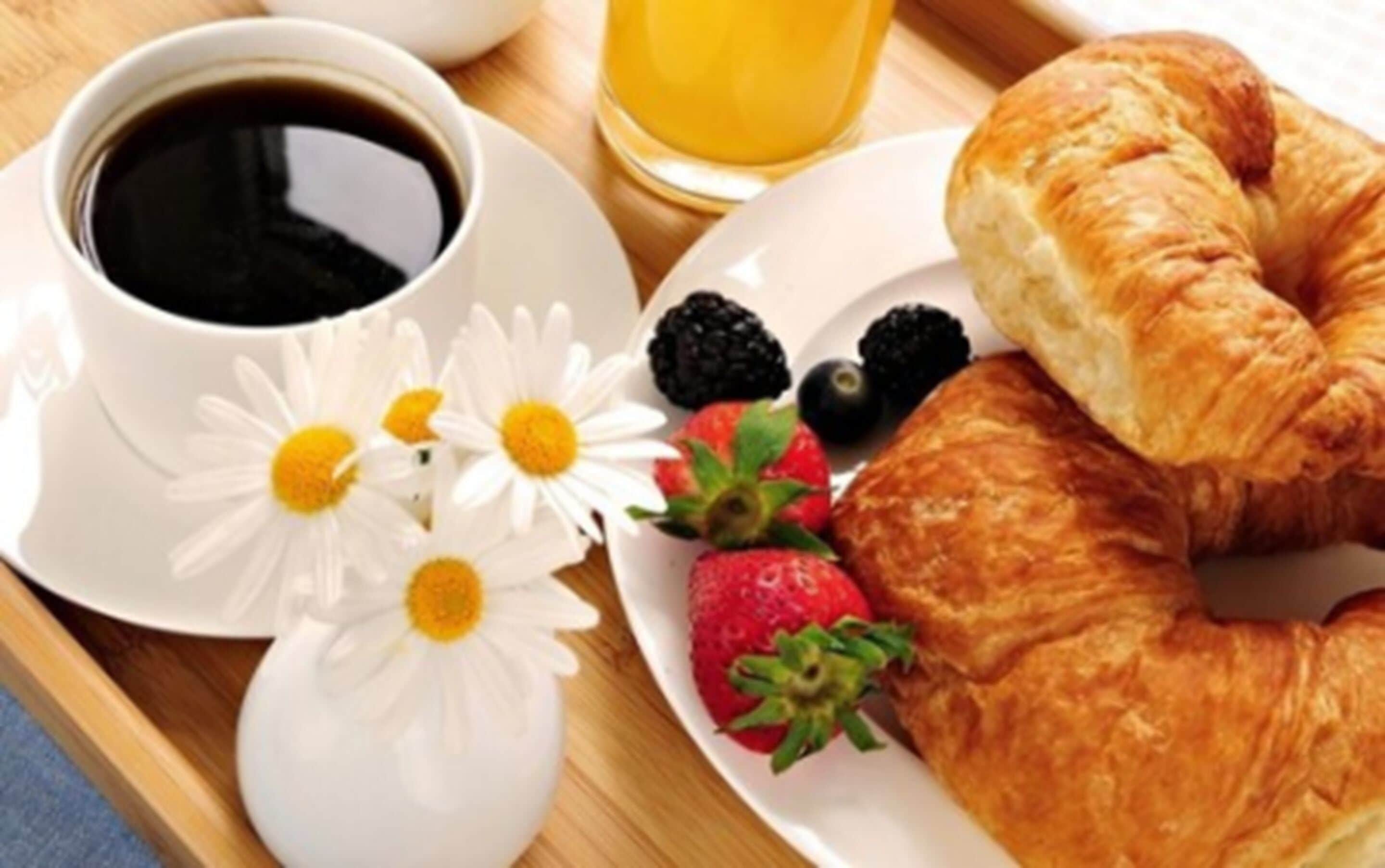 Bandeja de desayuno con un croissant, fresas, zarzamoras, un vaso de jugo de naranja y una taza de café.