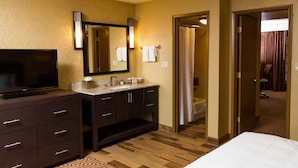 A hotel room with a large flat-screen TV, a vanity with a mirror, a bathtub, and a separate shower area. - DoubleTree Suites by Hilton Tucson - Williams Center (Tucson)