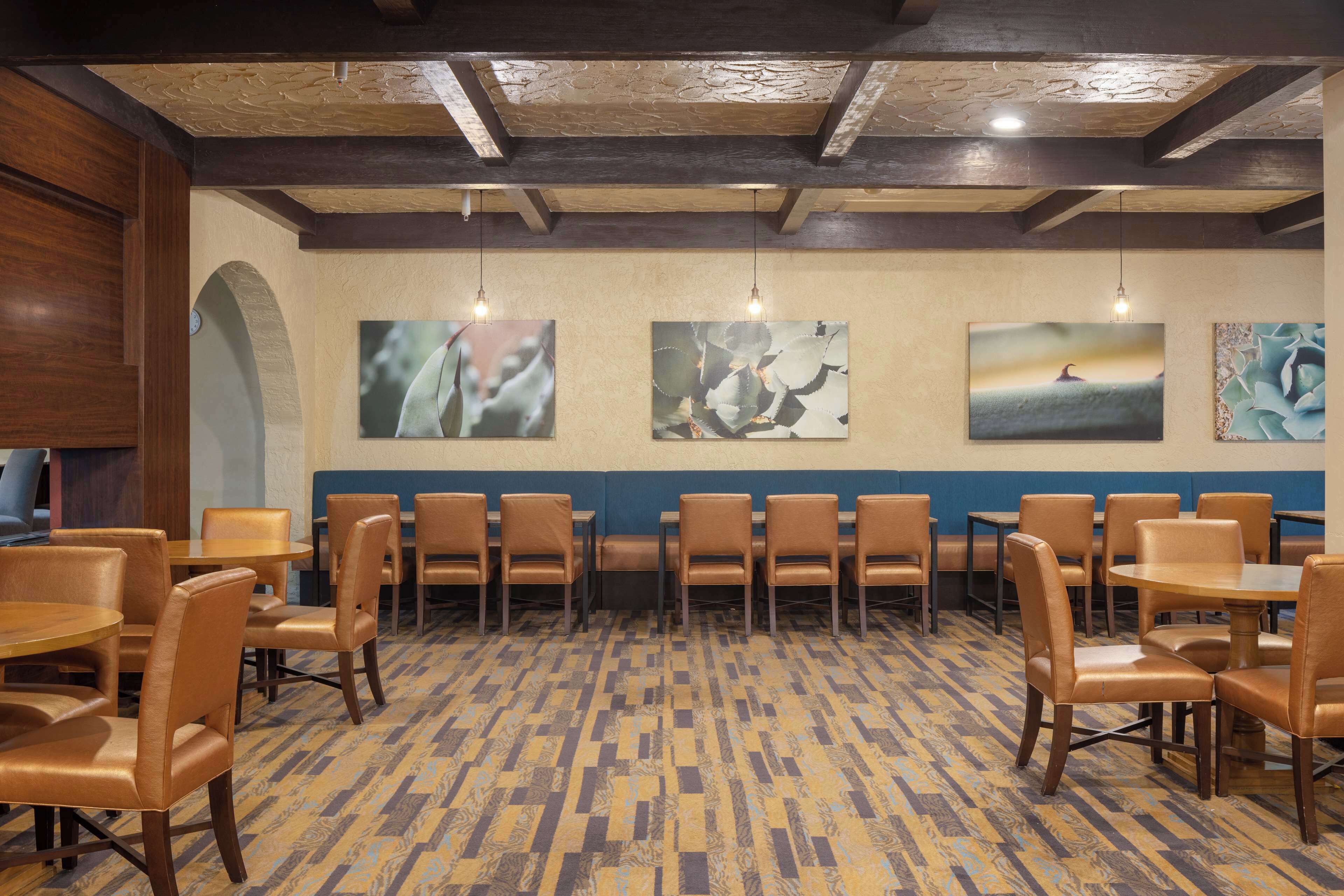 A restaurant with wooden tables and chairs, a patterned floor, and artwork on the walls.