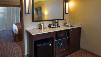 A hotel bathroom with a sink, microwave, and a small refrigerator.