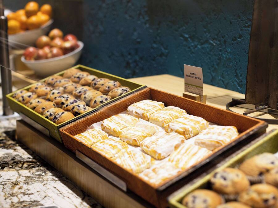 Una vetrina di panetteria con diverse preparazioni da forno, tra cui muffin e dolci, disposti in scatole di legno.