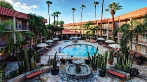 A pool area with lounge chairs, umbrellas, and a fountain surrounded by cacti and palm trees. - DoubleTree Suites by Hilton Tucson - Williams Center (Tucson)