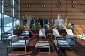 Ein moderner Außenbereich mit Lounge-Möbeln und Tischen, umgeben von Holzverkleidung und Zierpflanzen.