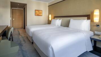 Une chambre d’hôtel avec deux lits, un bureau et une chaise.
