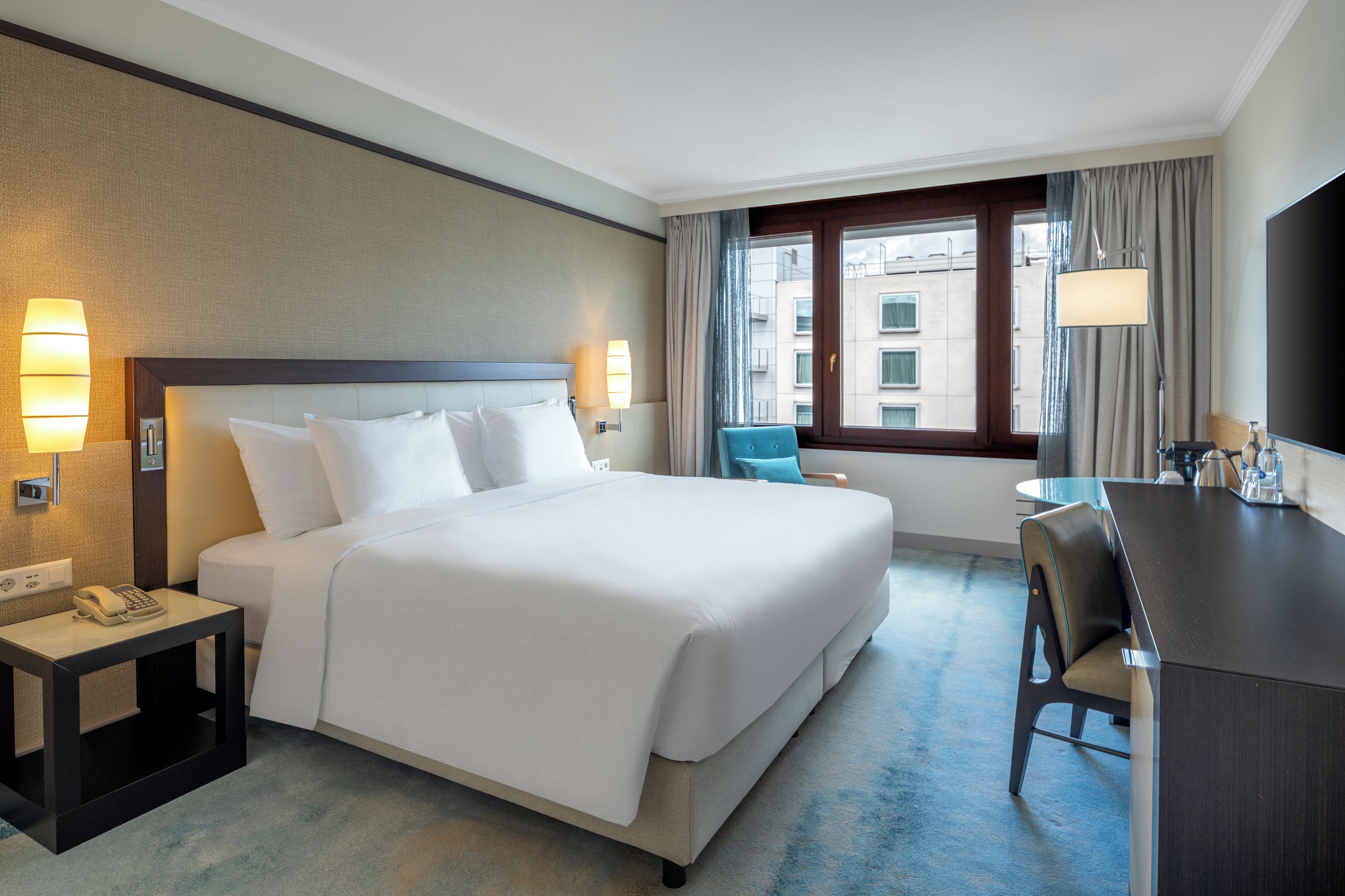 Une chambre d’hôtel avec un grand lit, des lampes de chevet, un bureau et une chaise.