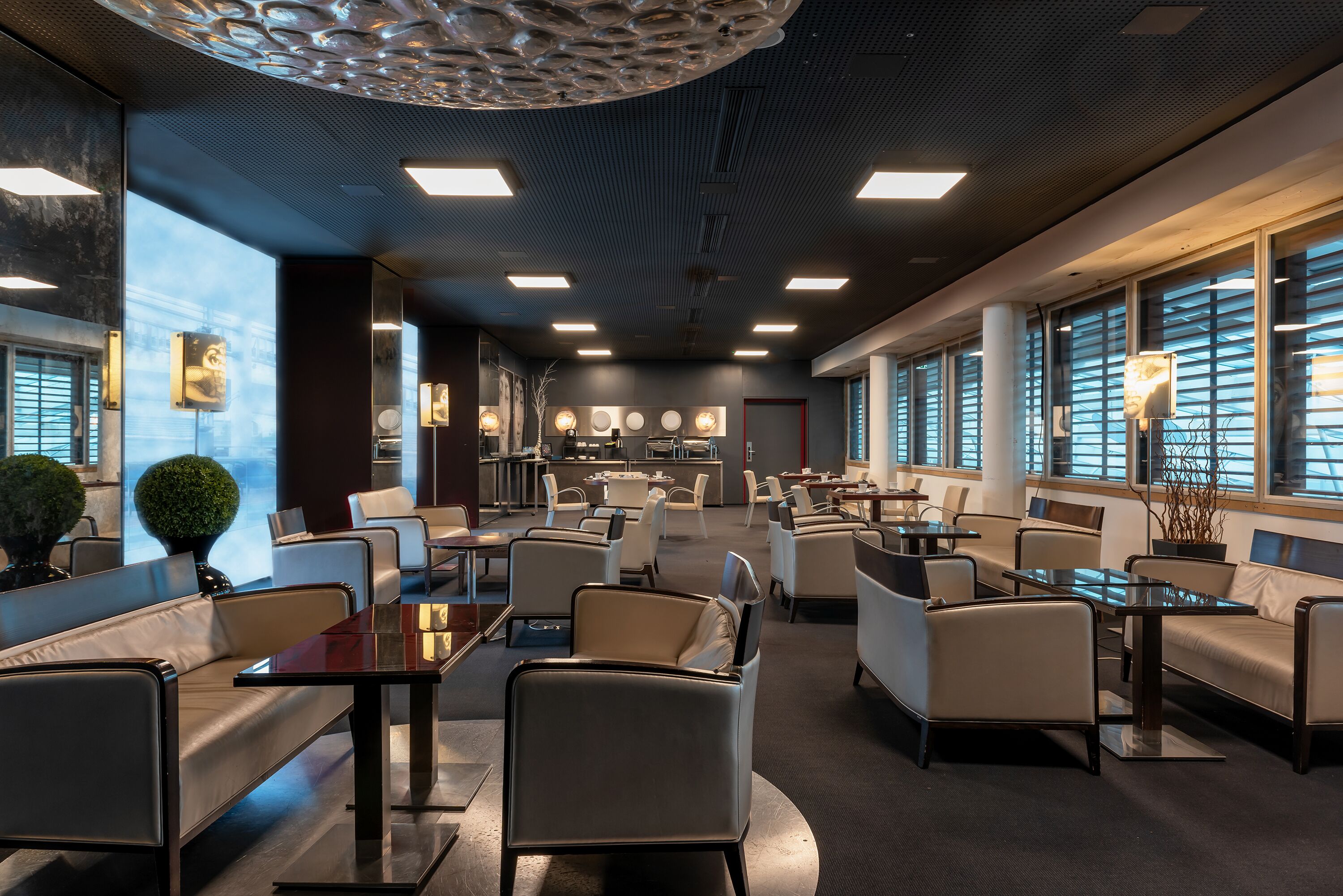 A modern hotel lobby with seating areas, a reception desk, and large windows.
