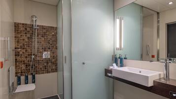 A modern bathroom with a glass shower enclosure, a white sink, and a mirror.