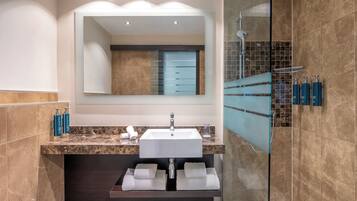 Une salle de bain moderne avec un lavabo en marbre, un grand miroir et une douche à parois de verre.