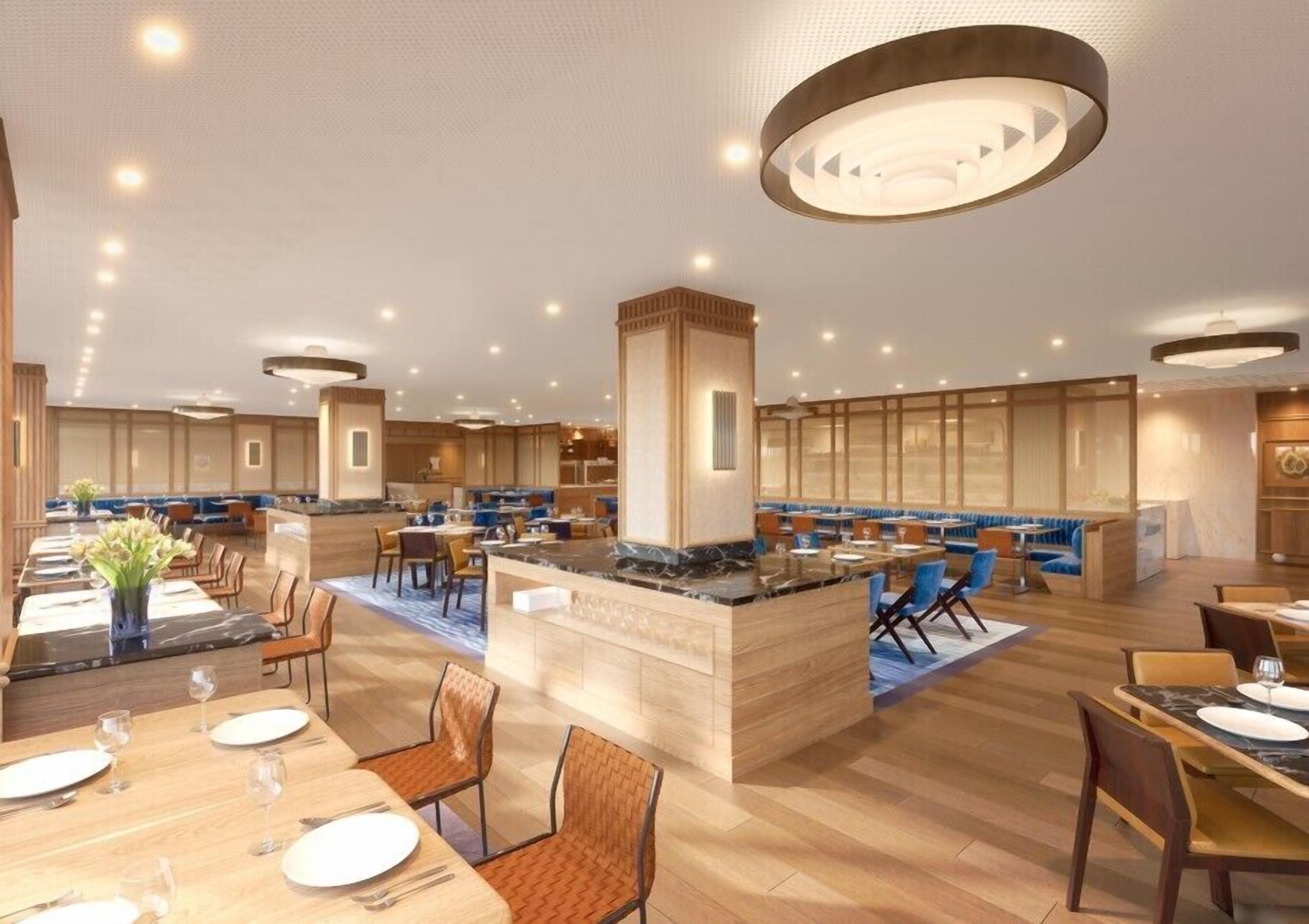 Un moderno vestíbulo de hotel con una isla central, zonas de estar y un bar.
