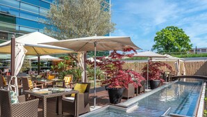 A rooftop pool area with outdoor seating and umbrellas. - Hilton Geneva Hotel and Conference Centre (Le Grand-Saconnex)