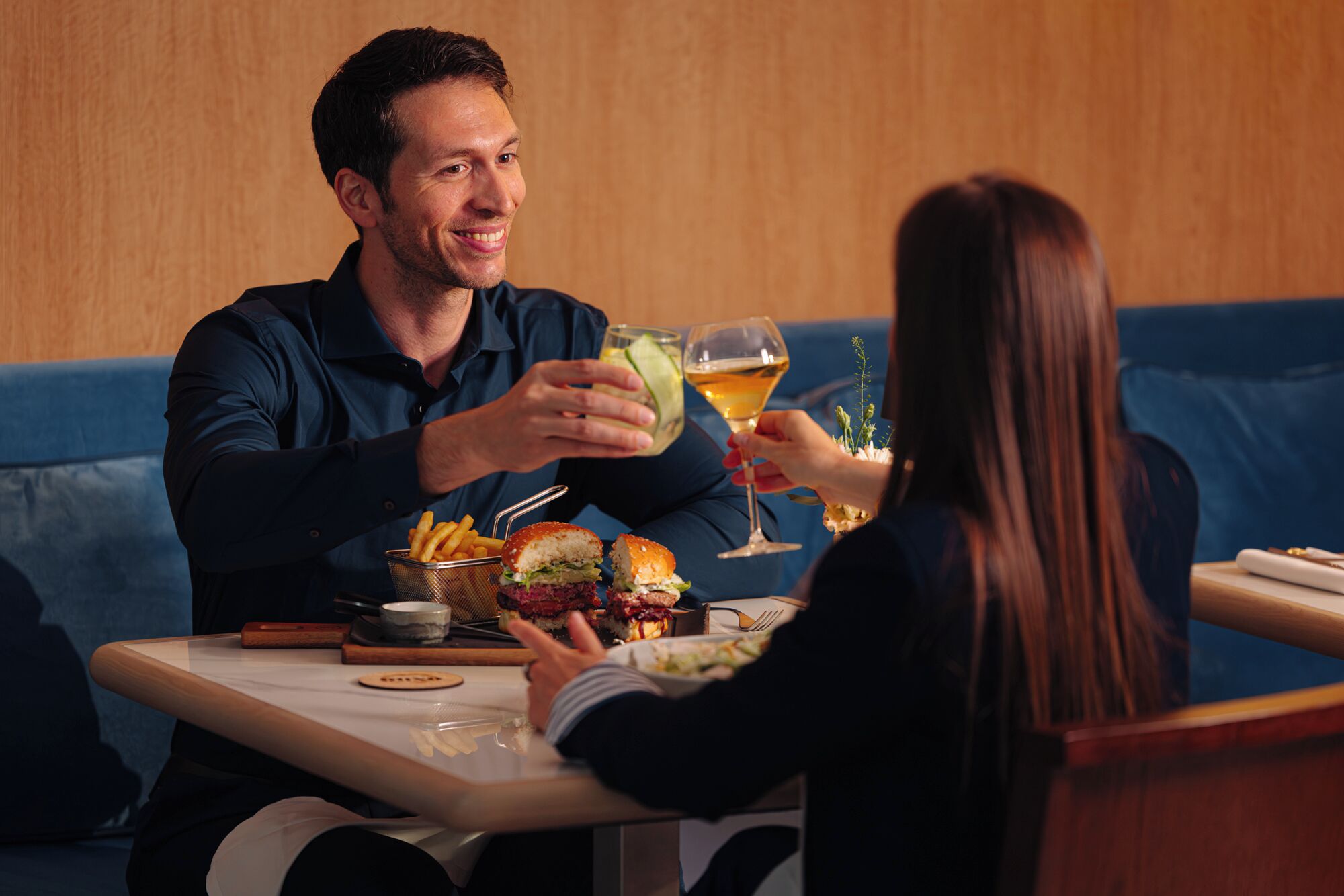 A dining table with food and drinks, a blue couch, and a wooden wall.
