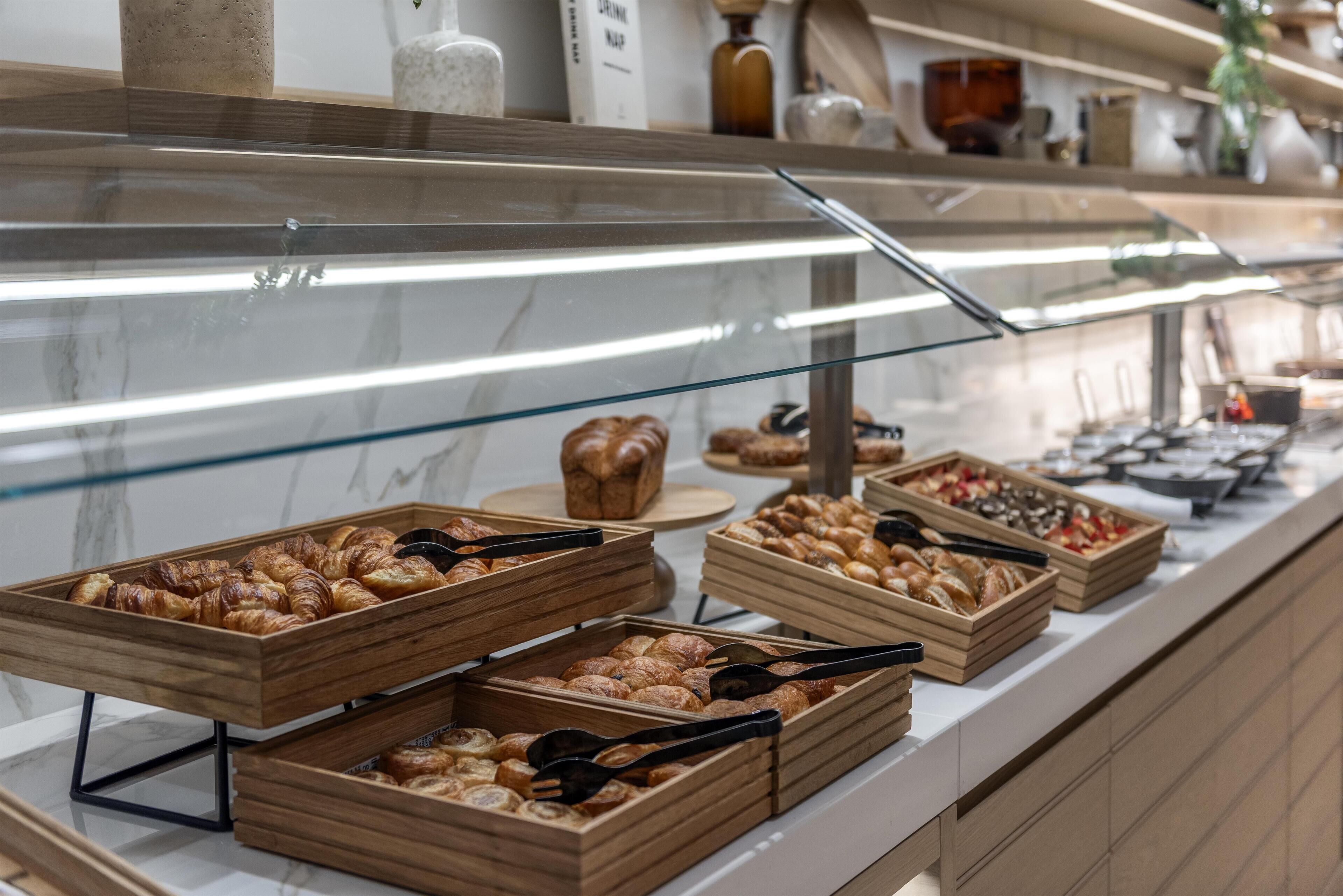 Un buffet avec des plateaux en bois remplis de pâtisseries et une vitrine réfrigérée.