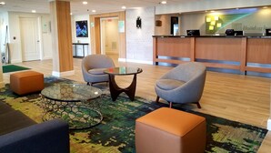 Un hall con dos sillones, una mesa de centro de cristal y un mostrador de recepción.