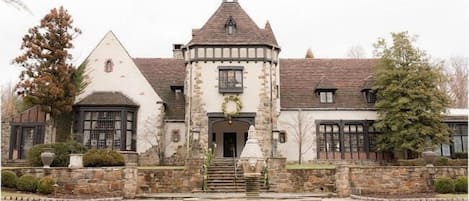A historic building with a central tower, stone walls, and a paved courtyard.