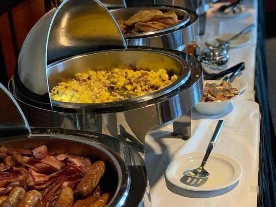 Un bufé con diversos platos en recipientes metálicos.