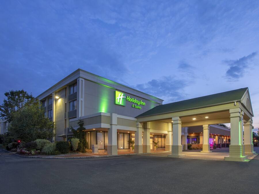A Holiday Inn & Suites building with a covered entrance and a landscaped garden area.