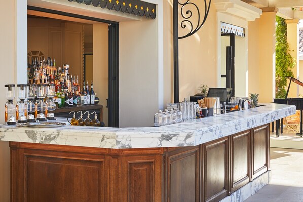Una zona de bar con encimera de mármol, varias botellas y una máquina de café.