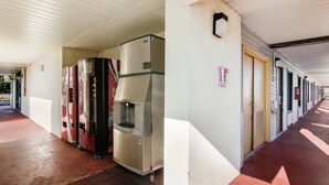 A covered corridor with a row of refrigerators and a water dispenser, a fire alarm, and a door with a handle. - Econo Lodge Conyers (Conyers)
