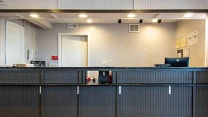 A reception desk with a computer, a door, and a wall-mounted security camera. - Econo Lodge Conyers (Conyers)