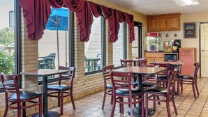 Un restaurant aux murs de briques, aux grandes fenêtres et aux tables et chaises en bois.