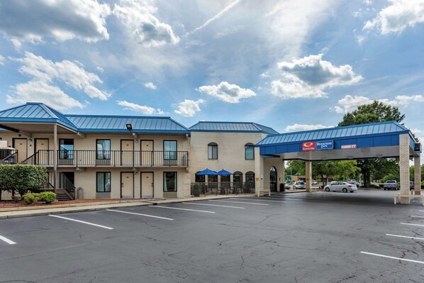 A motel with a blue roof and a covered parking area.