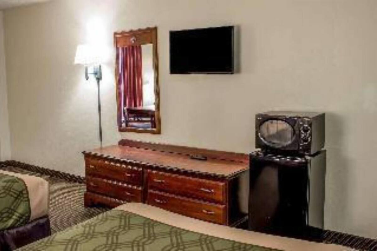 A bedroom with a bed, a dresser, a television, and a mirror.