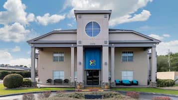 A building with a central entrance, columns, and a blue awning with a logo.