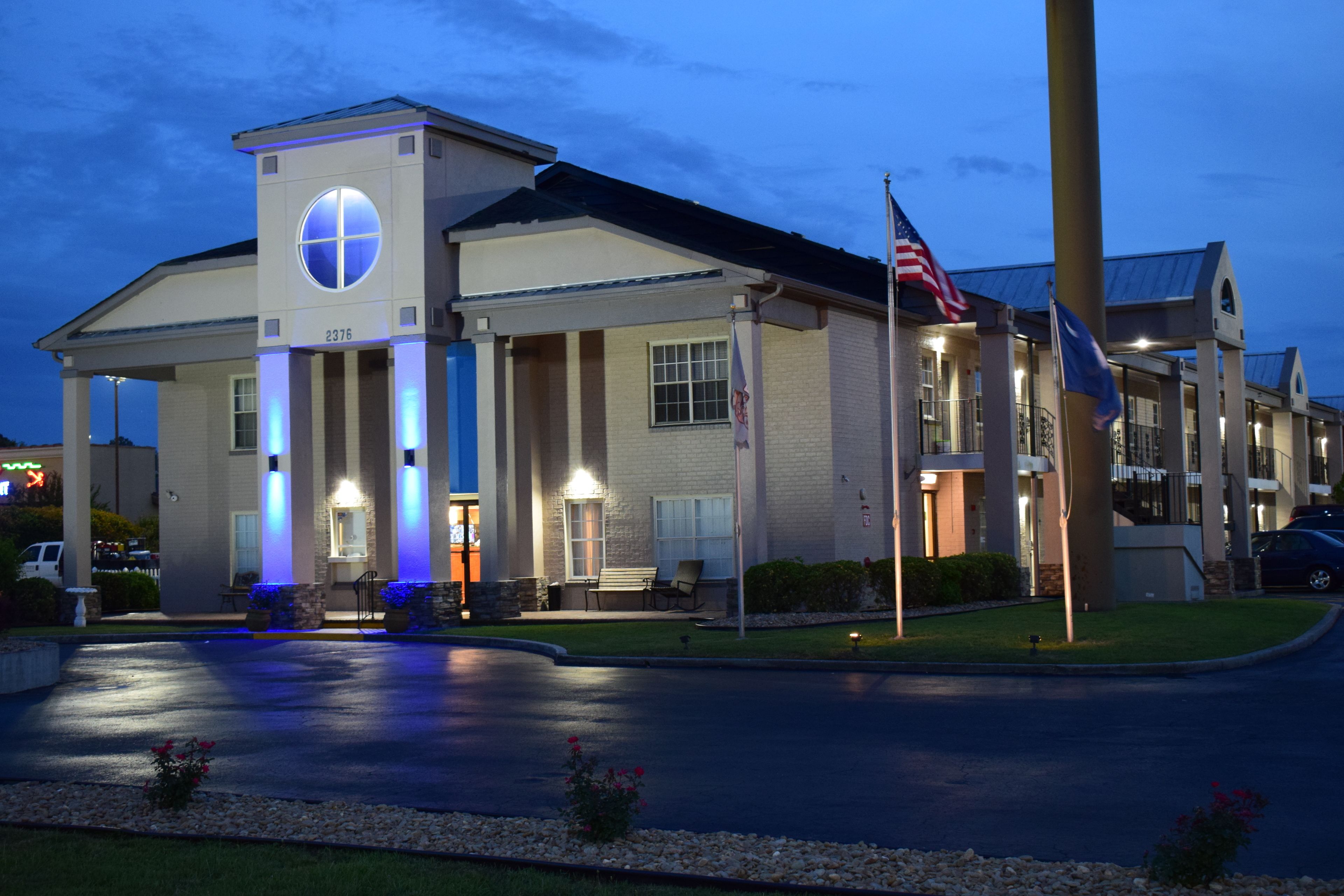 A hotel with a prominent entrance, a flagpole with an American flag, and a well-lit building facade.