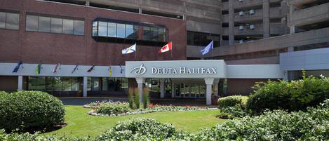 A Delta Halifax hotel with a brick facade, multiple flags, and a well-maintained garden.