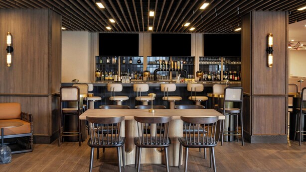 A bar area with a long counter, multiple stools, and a bar stocked with bottles.
